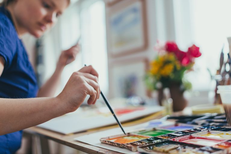 Picture of a person dipping their paintbrush in paint